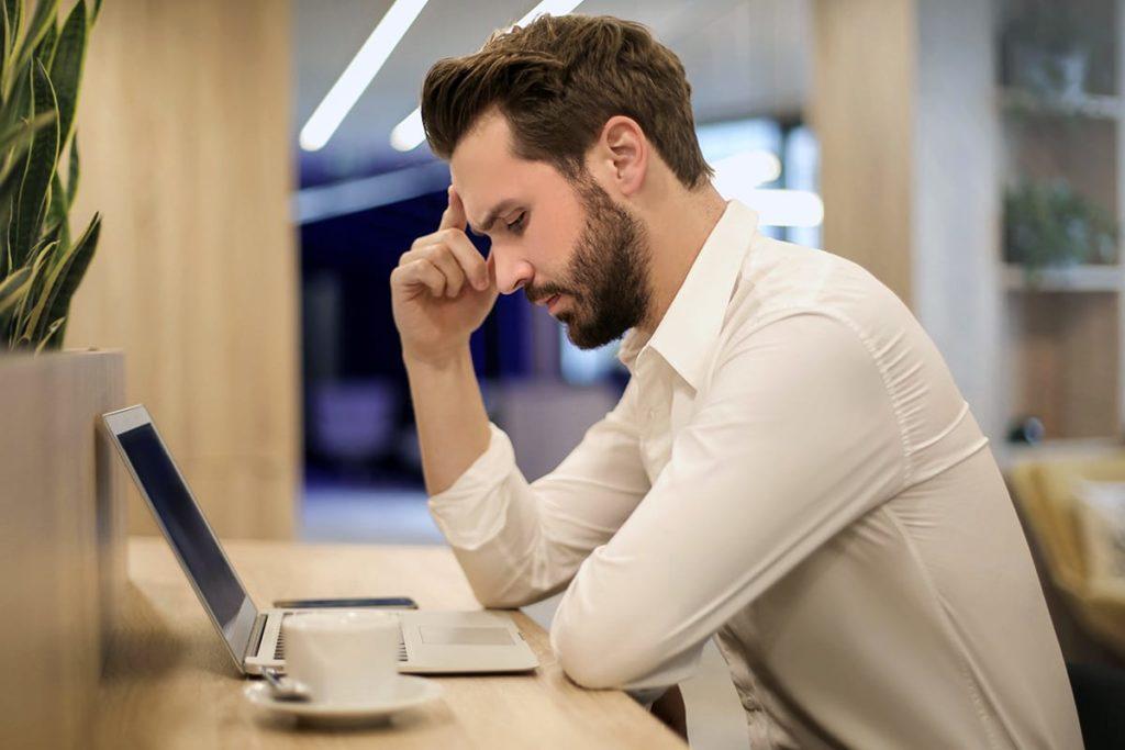 Mann mit Konzentrationsproblemen vor einem Laptop